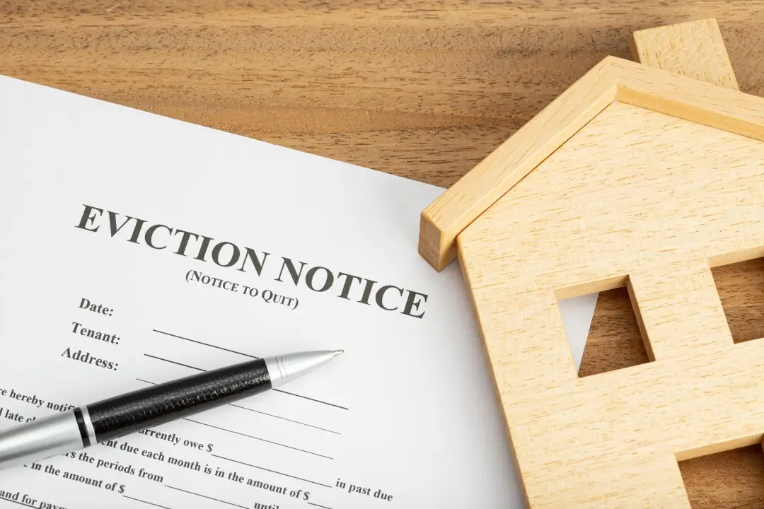 Eviction notice on a desk with a pen and wooden model house