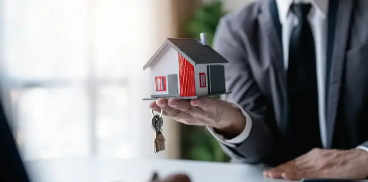 Hands holding a small model house representing home ownership
