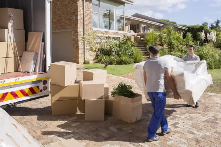 Two men carrying a couch to a moving truck full of boxes