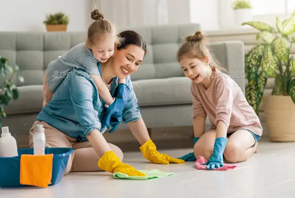 Happy family at home. Mother and daughters doing the cleaning in the house. A young woman and children girls are dusting. Cute little helper.