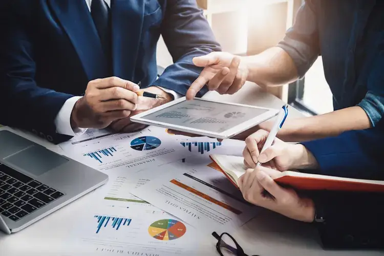 Business professionals reviewing financial reports and charts on tablet