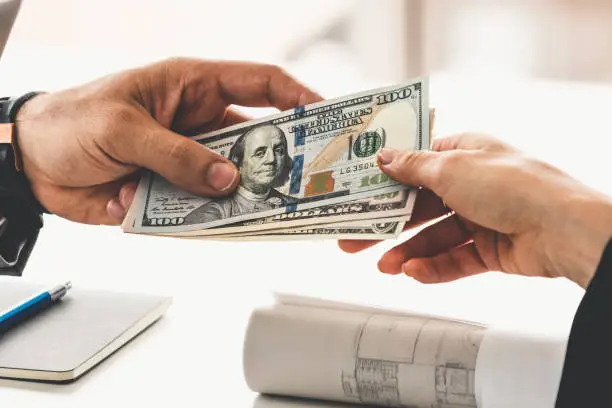 Person handing cash to another person during a transaction