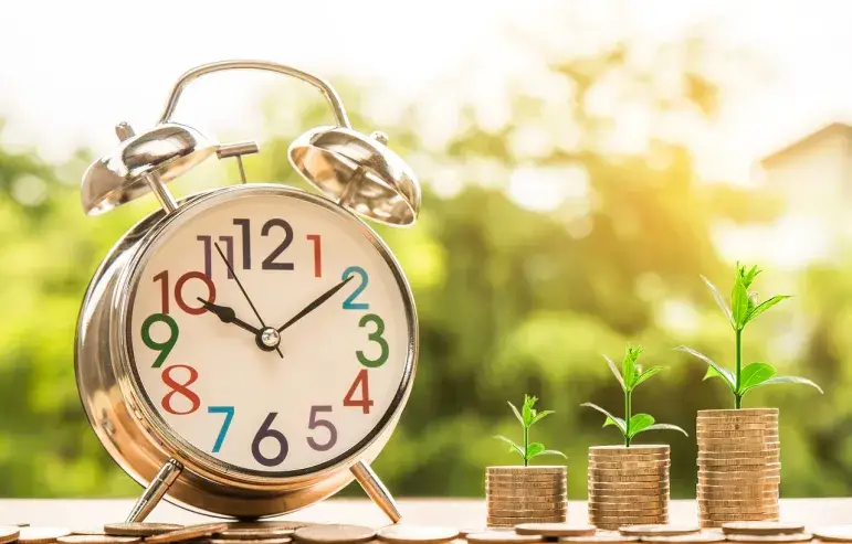 Stacked coins next to a clock representing time and money