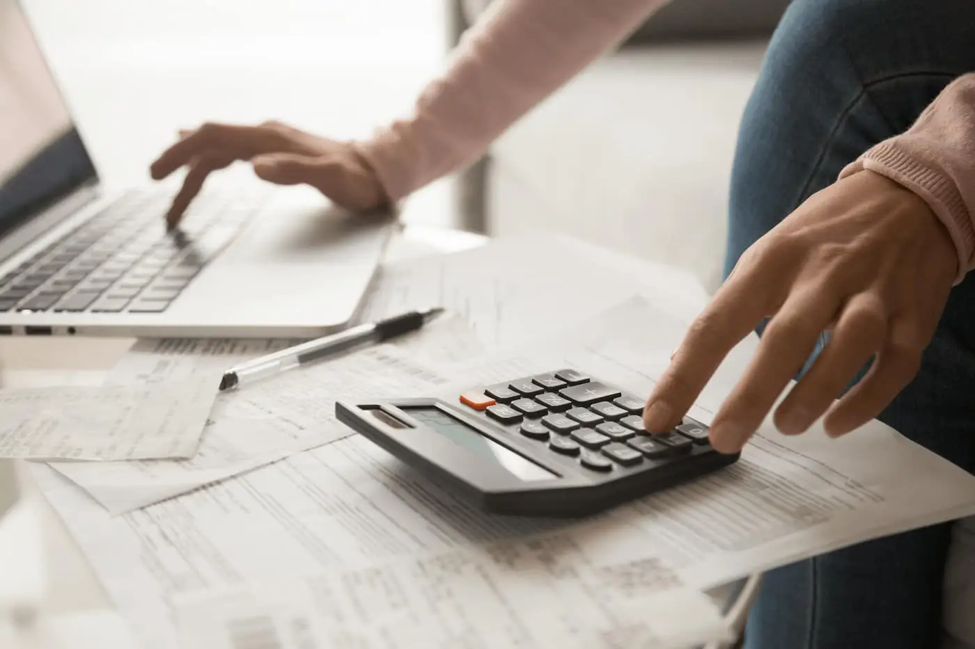 Person using calculator and paperwork for real estate or financial planning