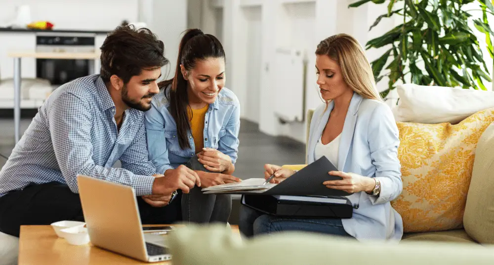 Couple meeting with real estate agent to review documents and discuss home buying or selling options