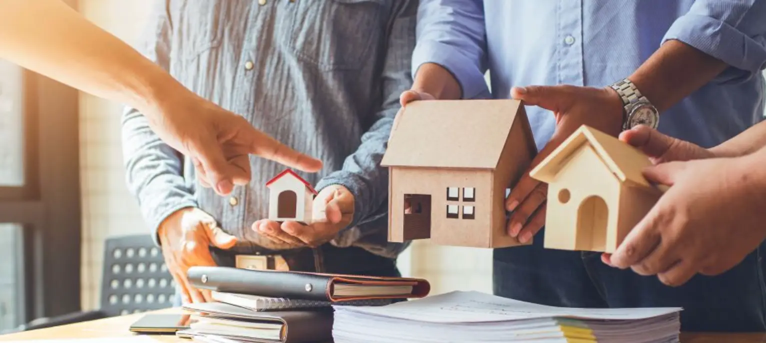 People discussing property with house models and documents