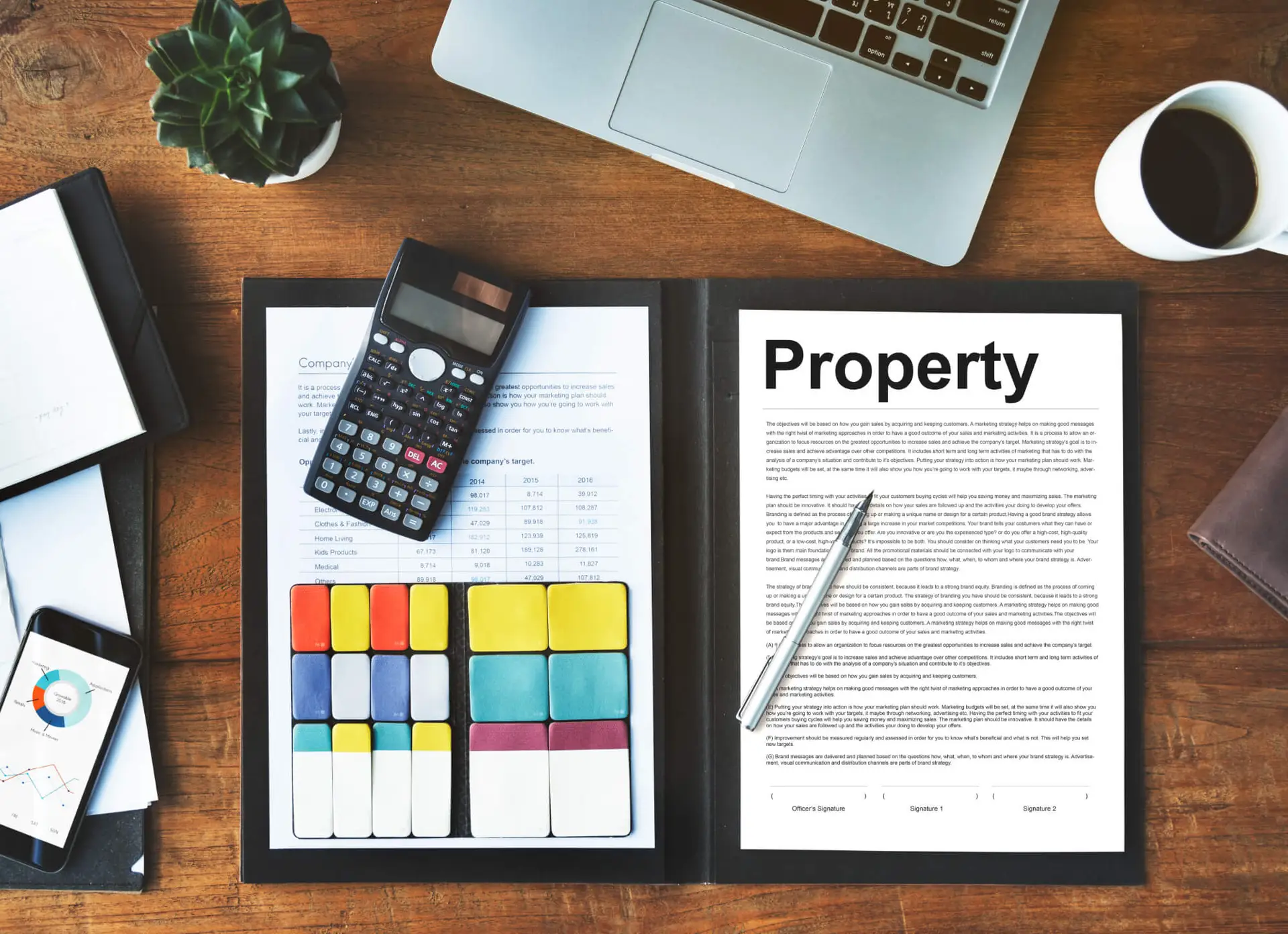 Open folder with property document, calculator, pen, and colorful charts on wooden desk
