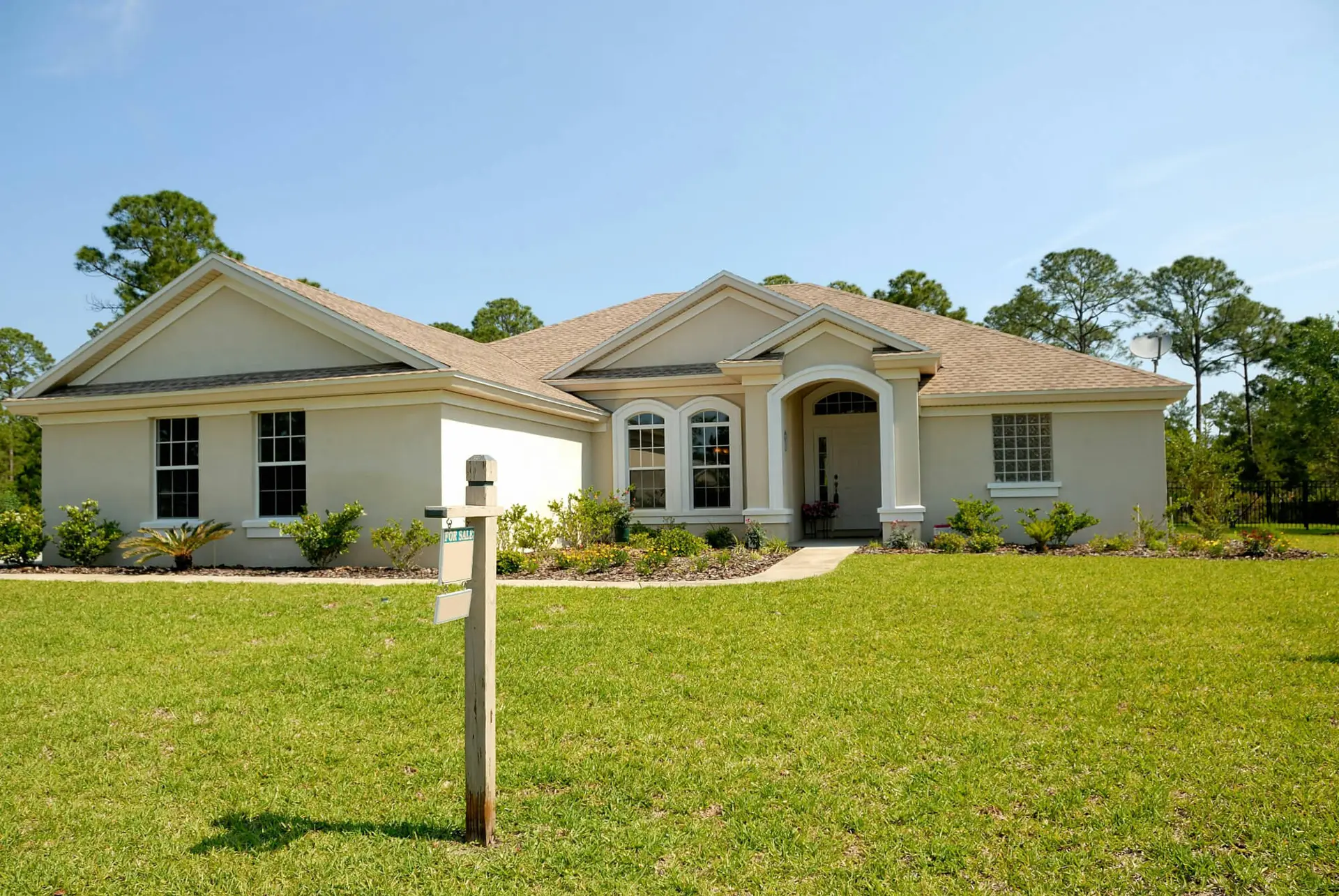 Single-story suburban home with front yard and clear blue sky