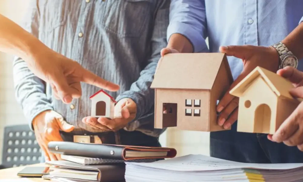 People discussing property with house models and documents